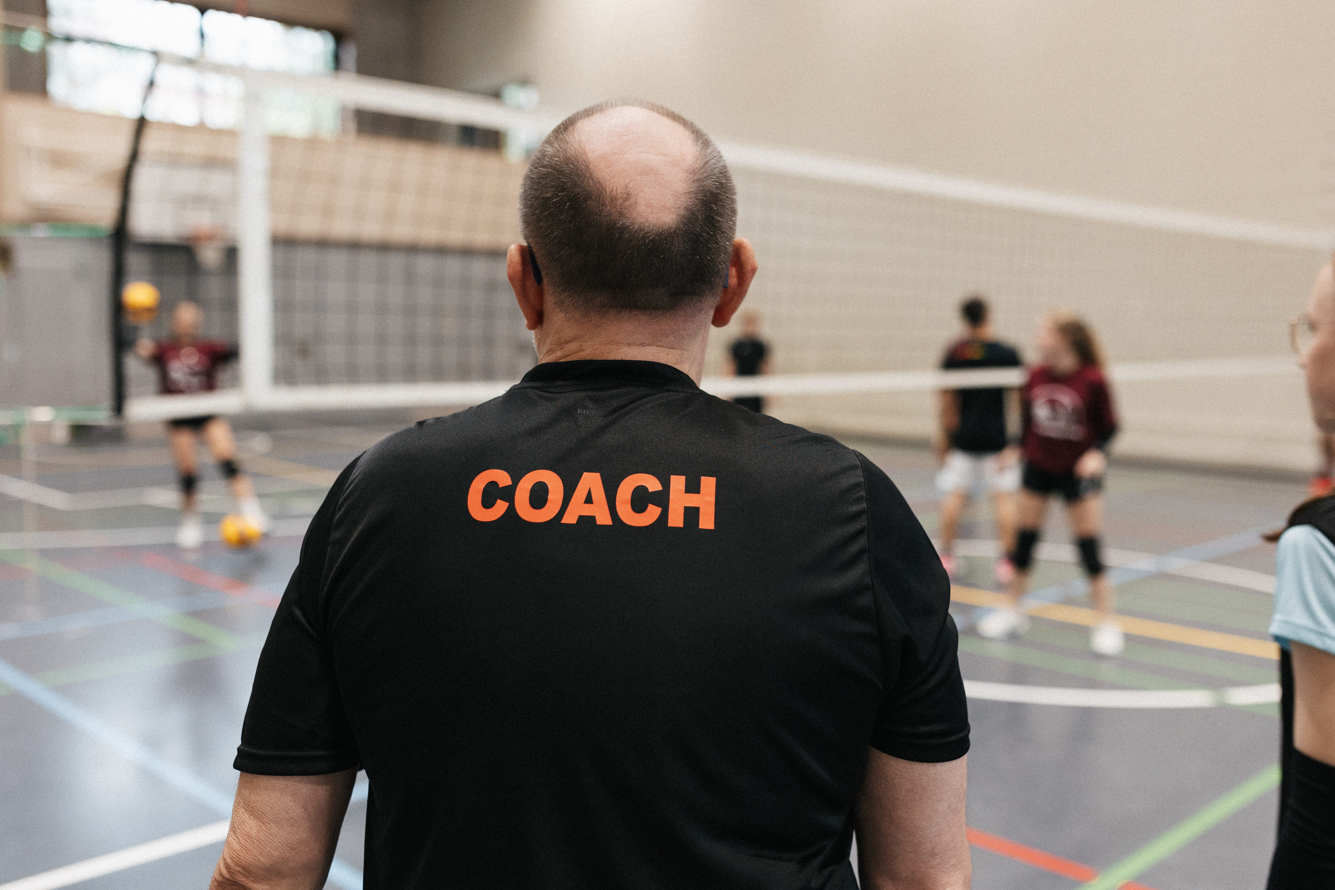 Coach von hinten fotografiert neben dem Feld stehend